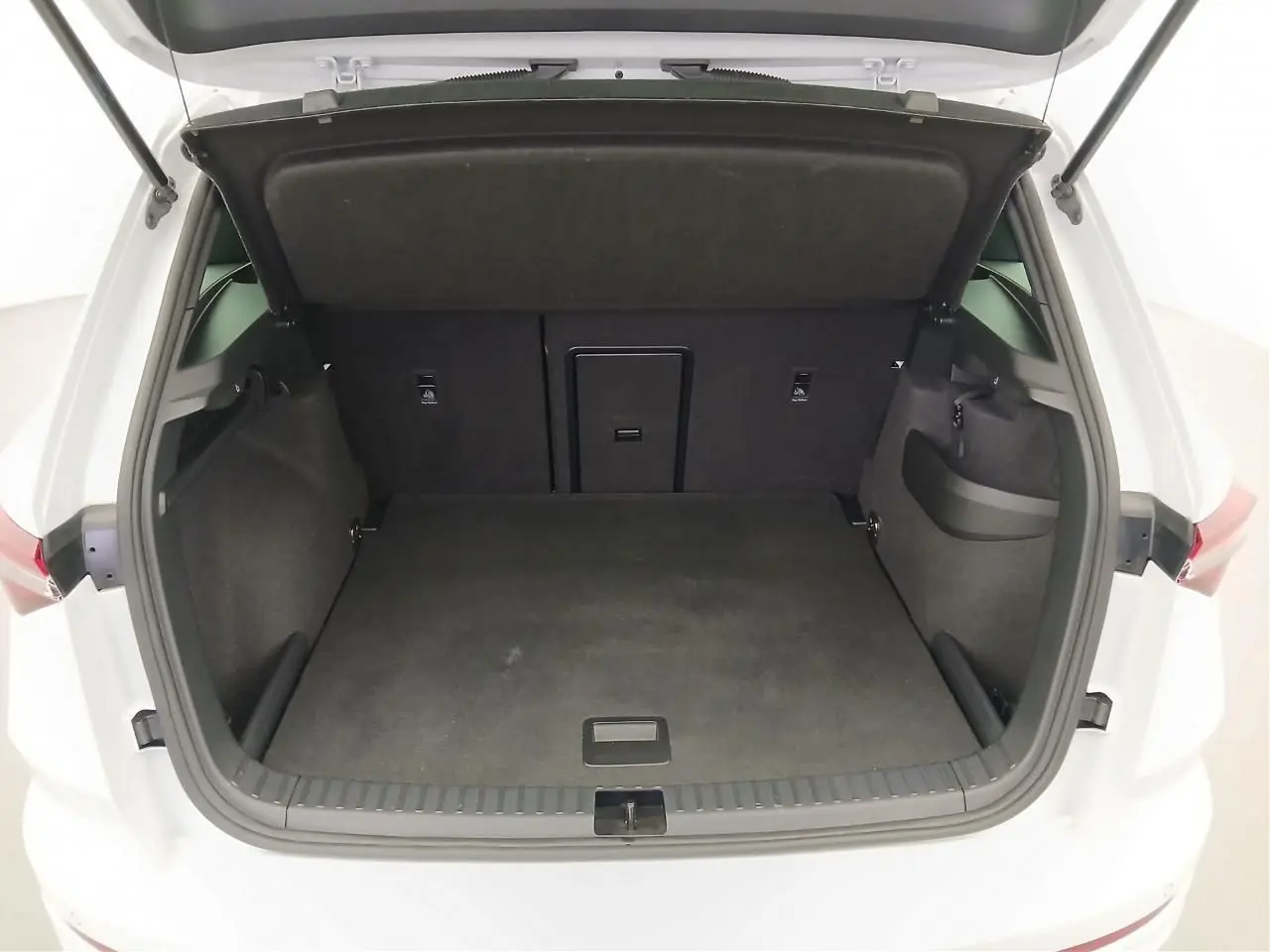 Coffre ouvert vu de l'arrière d'un Skoda Karoq Blanc Lune 2025, version 1.5 TSI 150 DSG7 Sportline, espace de chargement vide.