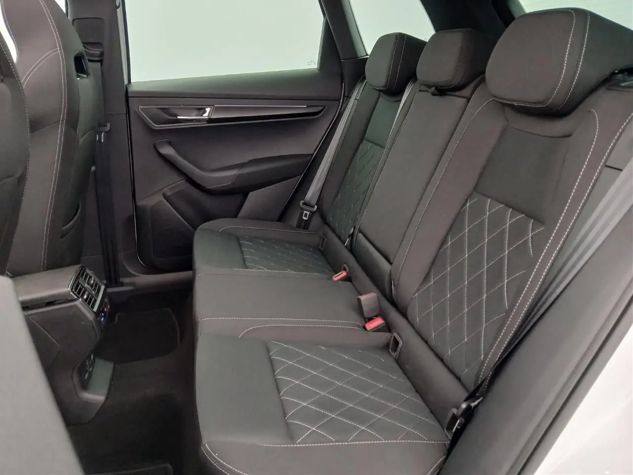 Vue intérieure côté droit des sièges arrière noirs avec surpiqûres blanches du Skoda Karoq 1.5 TSI 150 DSG7 Sportline 2025 blanc lune.