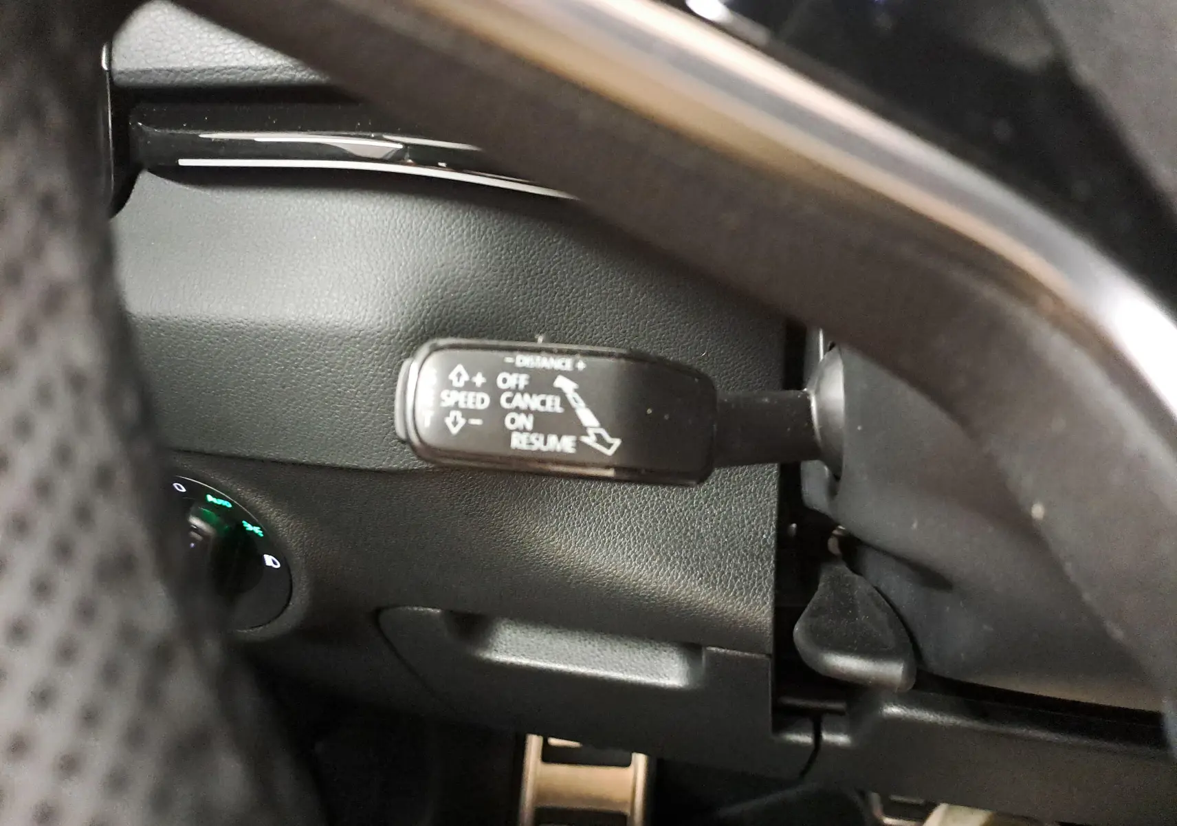 Gros plan sur la commande de régulateur de vitesse du Skoda Karoq 1.5 TSI blanc lune, côté gauche du volant.