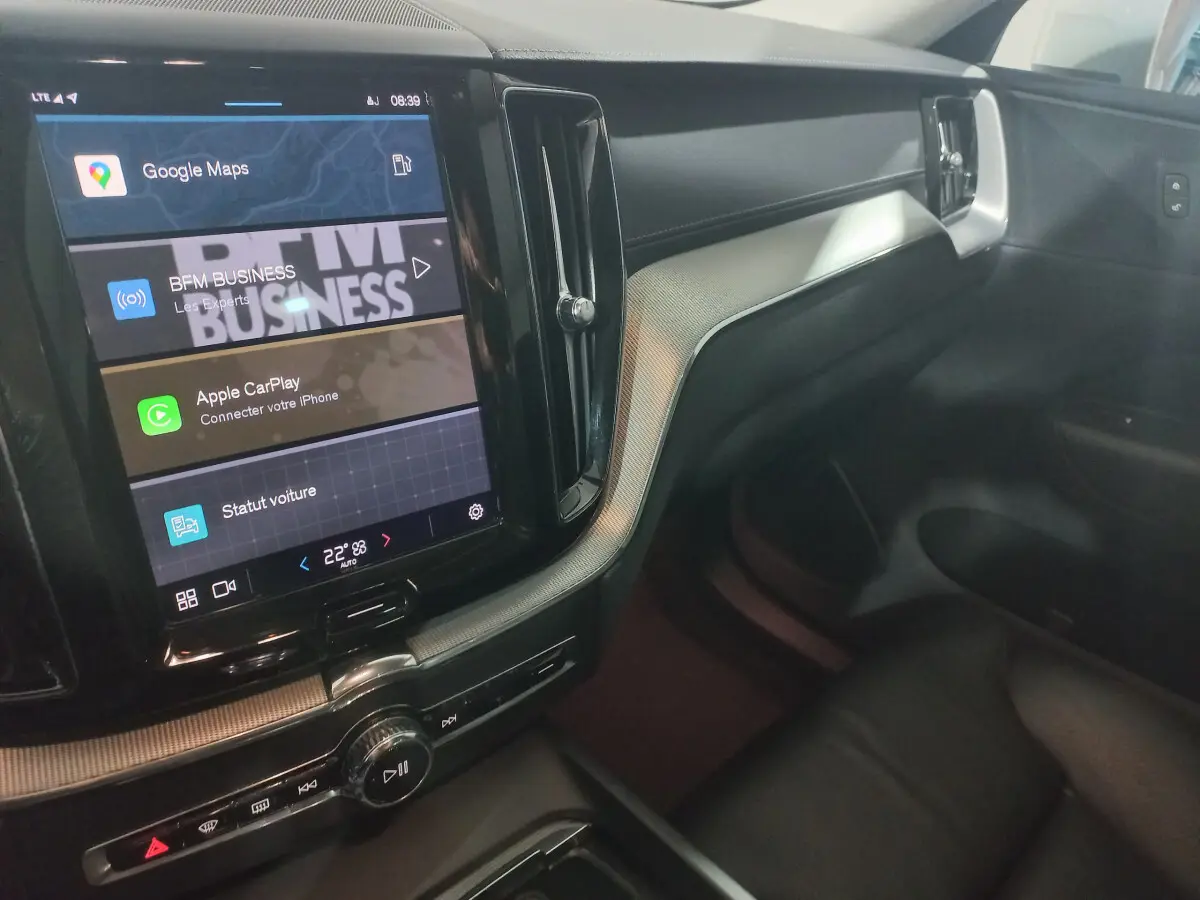 Vue intérieure côté passager du tableau de bord noir et écran tactile affichant Google Maps dans un Volvo XC60 gris clair.