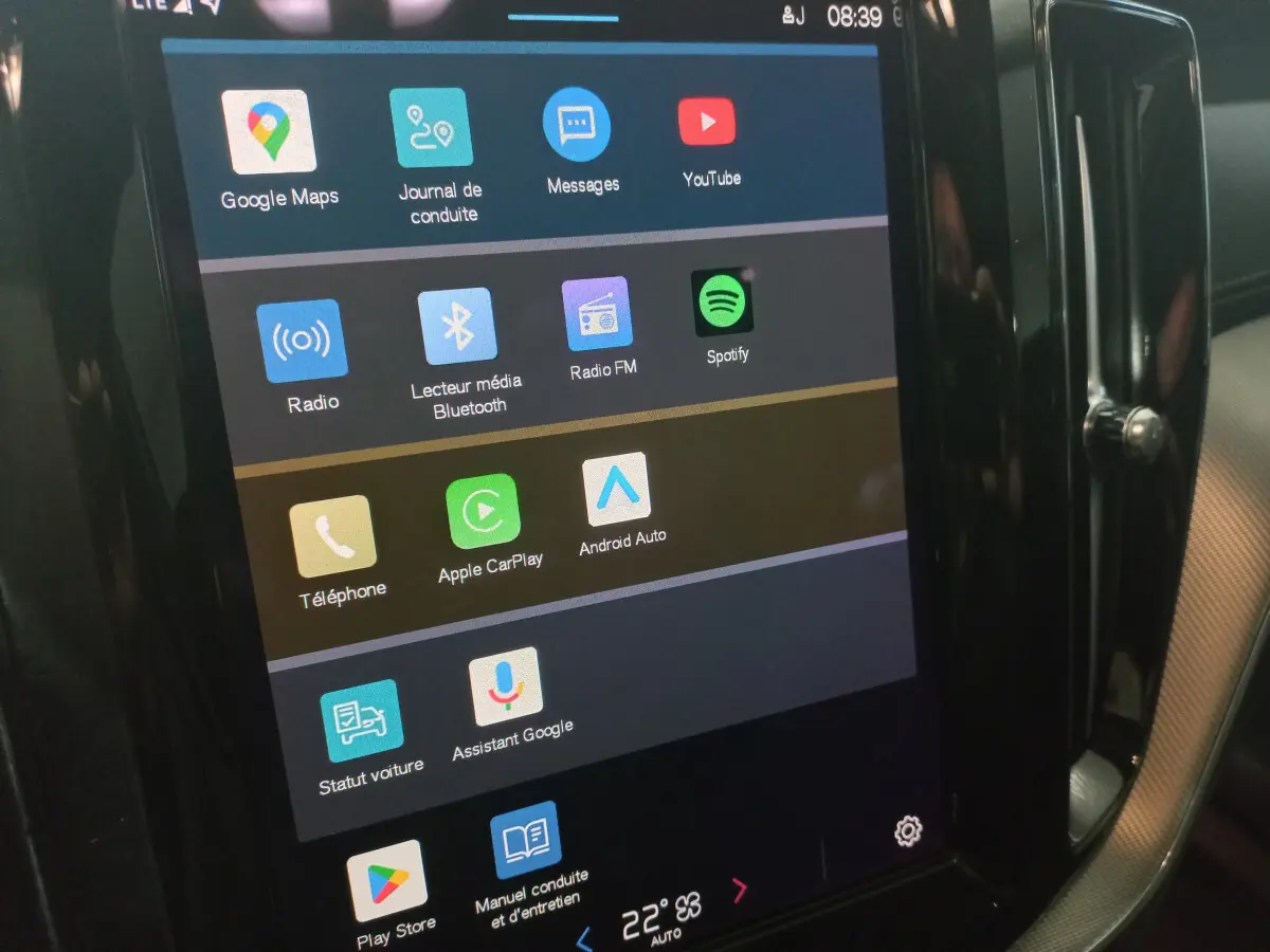 Écran tactile central du tableau de bord du Volvo XC60 gris clair, affichant les applications multimédia et connectivité.
