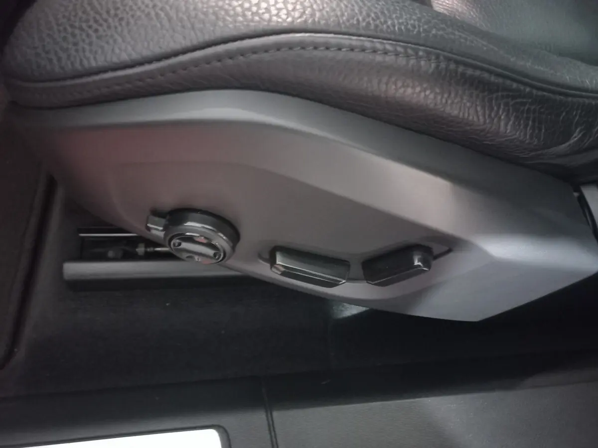 Gros plan sur les commandes de réglage électrique du siège conducteur en cuir noir du Volvo XC60 gris clair.