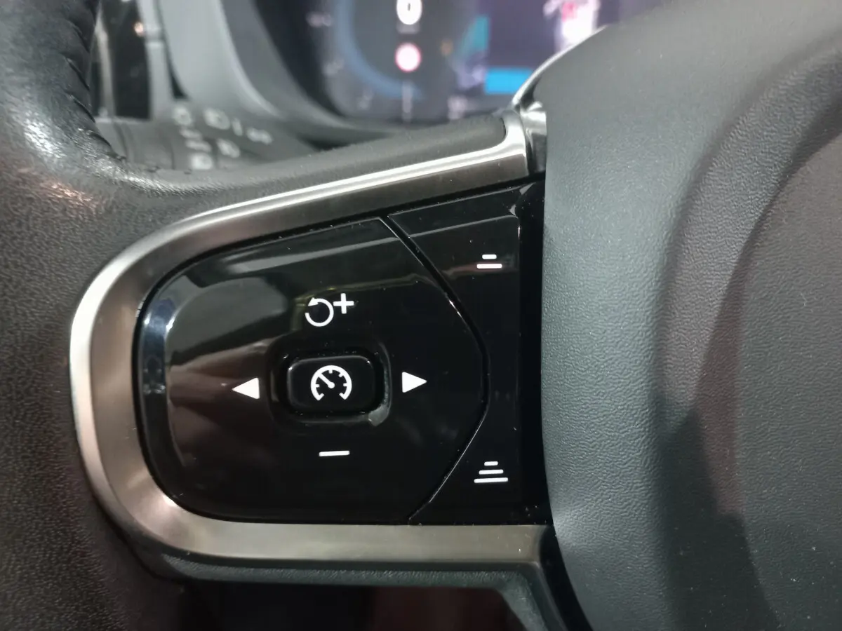 Gros plan sur les commandes de régulateur de vitesse au volant noir du Volvo XC60 gris clair B4 197 Geartronic 2022.