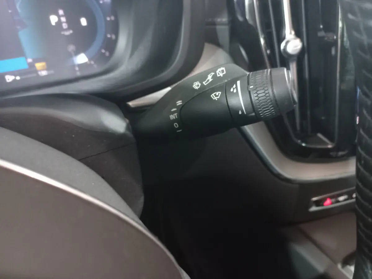 Gros plan sur la commande d'essuie-glaces noire à gauche du volant dans l'habitacle du Volvo XC60 gris clair 2022.