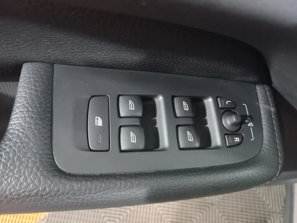 Boutons de commande des vitres et rétroviseurs sur la portière côté conducteur du Volvo XC60 gris clair 2022.