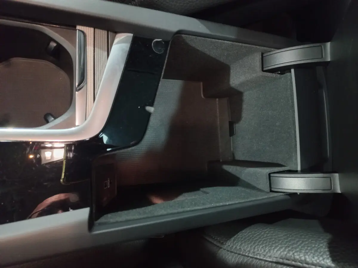 Vue rapprochée de la console centrale noire ouverte du Volvo XC60 B4 197 Geartronic 8 Inscription, intérieur gris.