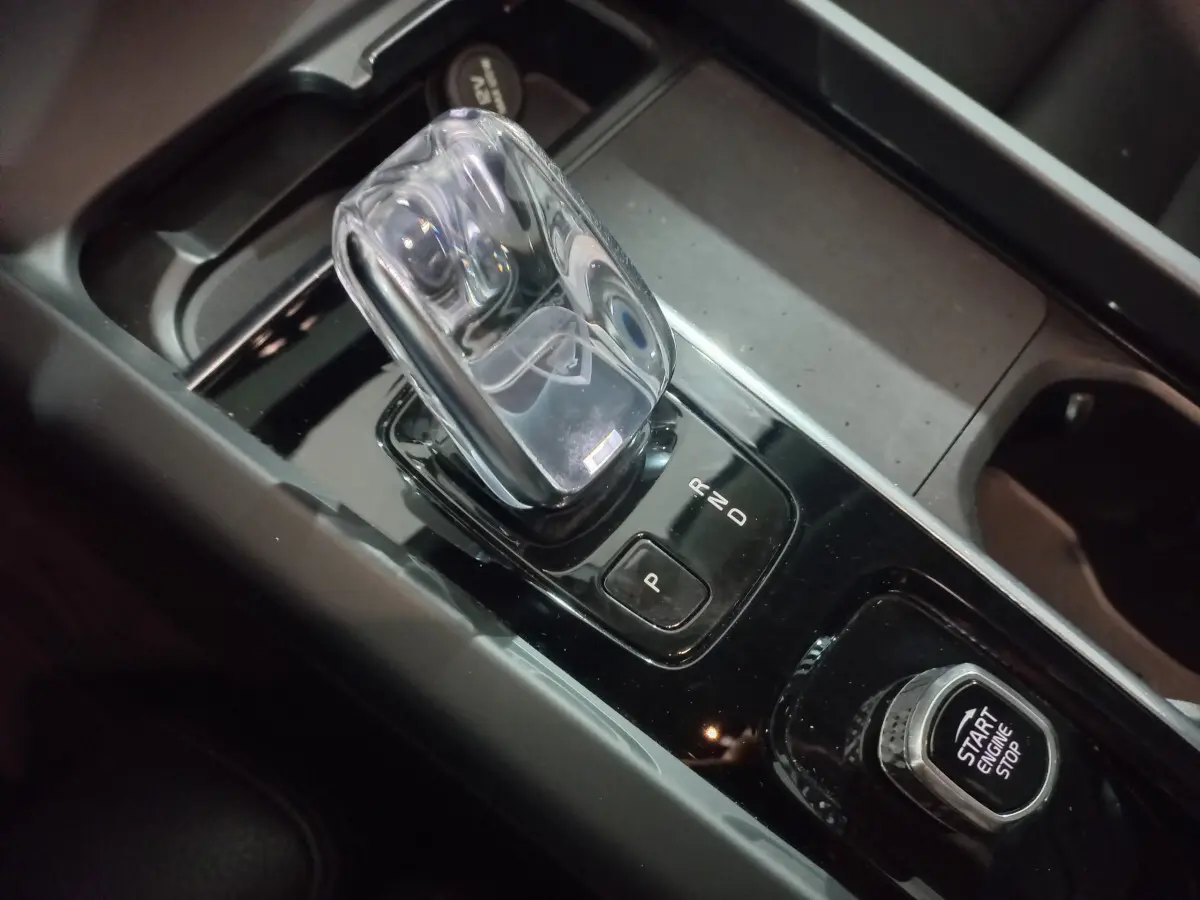 Gros plan sur la commande de boîte automatique et bouton start/stop du Volvo XC60 gris clair, intérieur moderne noir.