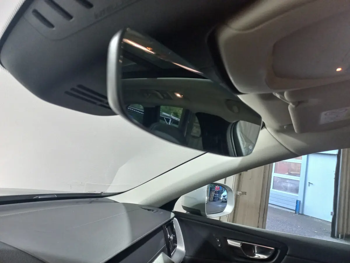 Intérieur du Volvo XC60 B4 2022, vue côté conducteur sur tableau de bord et rétroviseur gris clair.