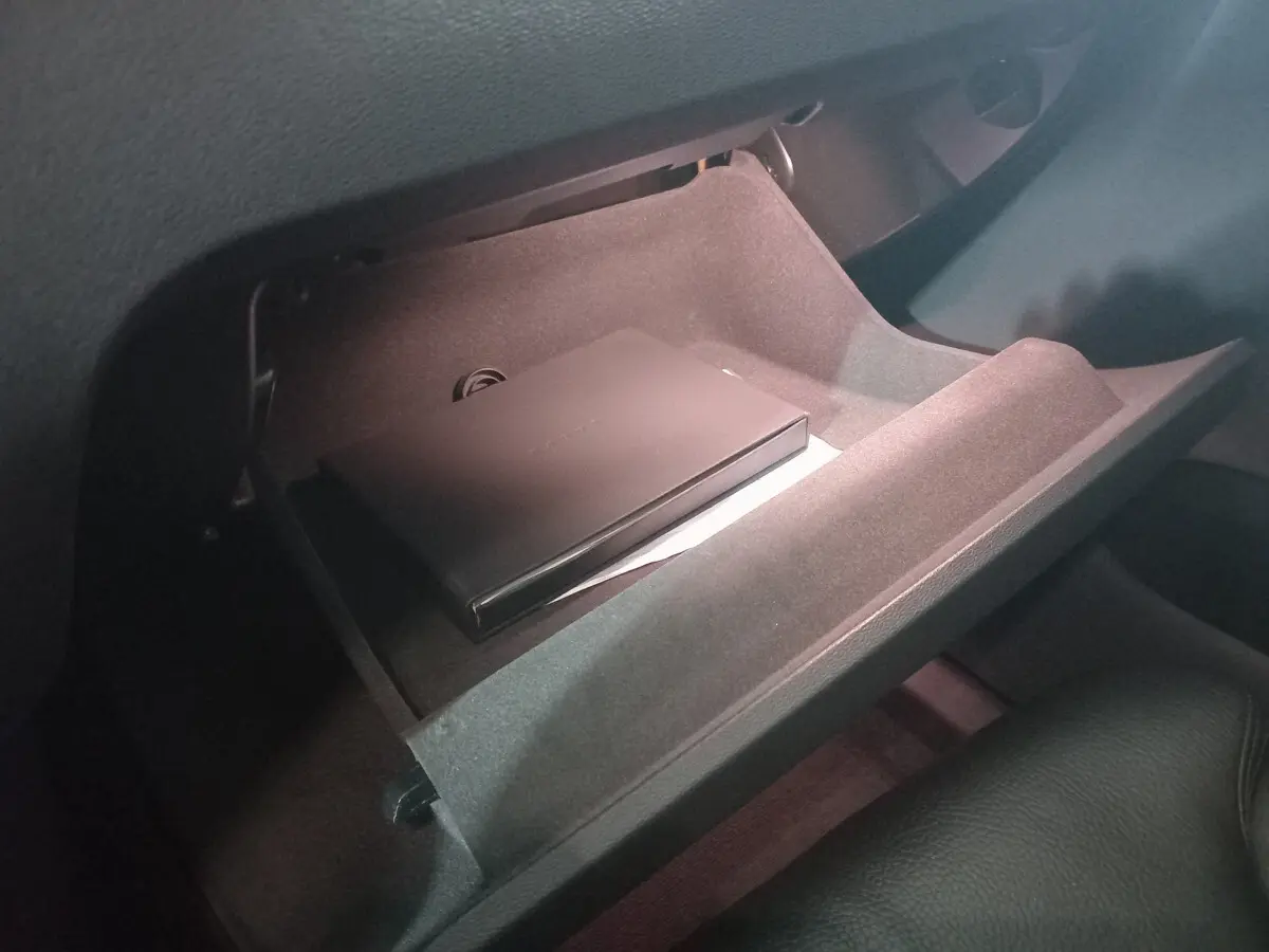 Gant de boîte ouvert côté passager du Volvo XC60 gris clair, montrant un boîtier noir à l'intérieur.