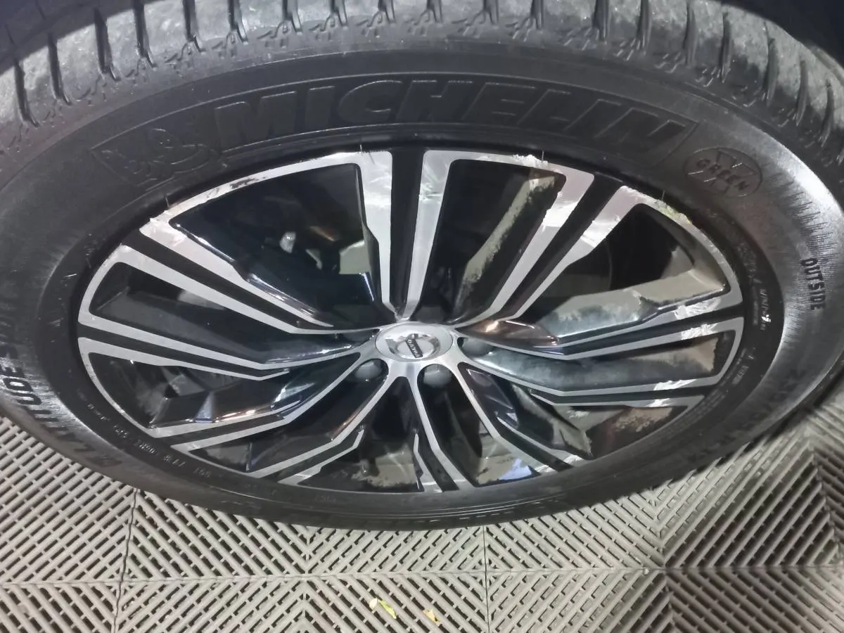 Gros plan sur la jante noire et argentée d'un Volvo XC60 gris clair avec pneu Michelin visible.