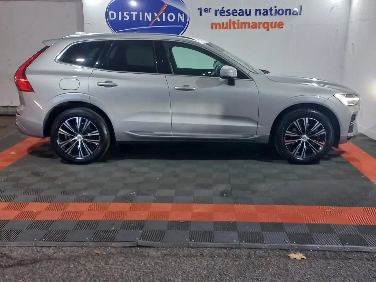 Profil droit d'un Volvo XC60 gris clair 2022 garé en intérieur avec jantes alliage et feux arrière distinctifs en L.