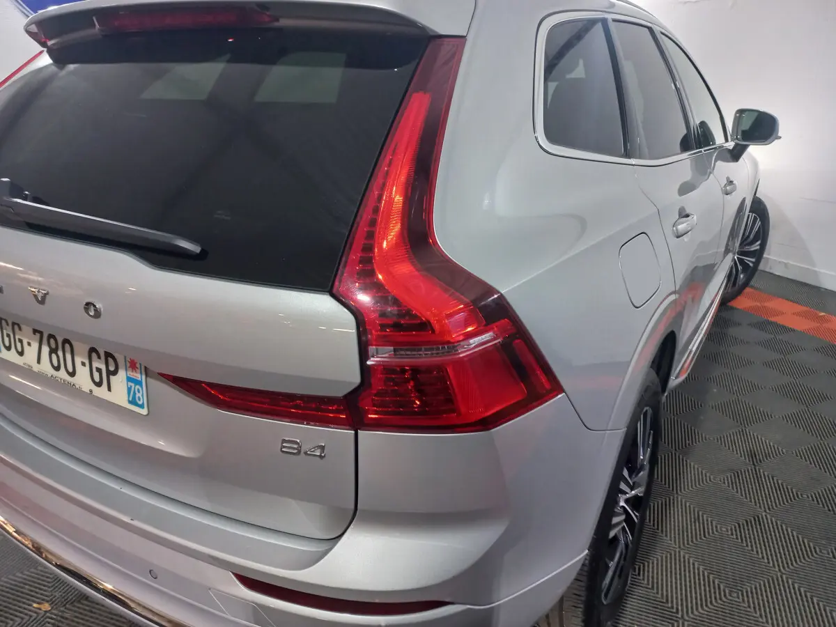 Vue 3/4 arrière droit d'un Volvo XC60 B4 gris clair avec feux arrière LED et jantes alliage noires.