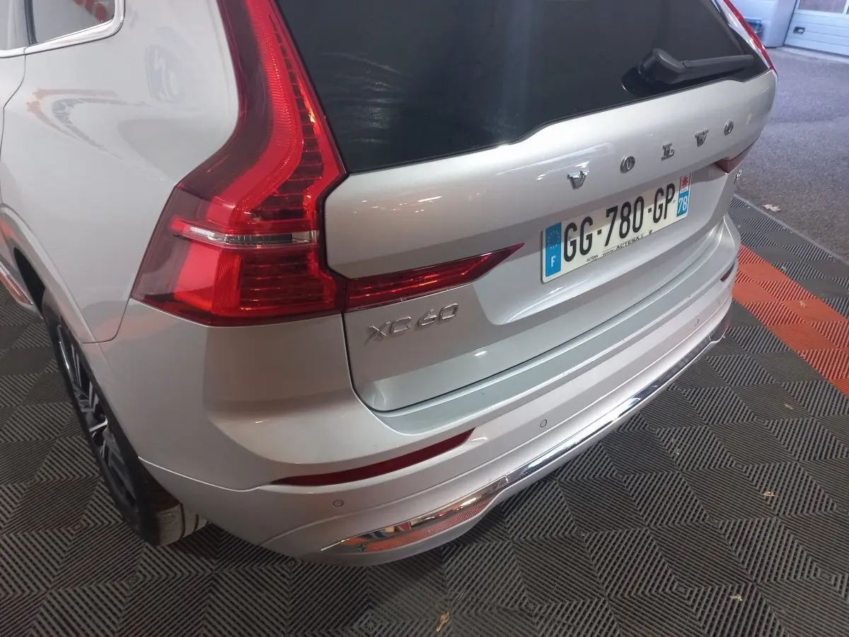 Vue 3/4 arrière droite d'un Volvo XC60 gris clair avec feux arrière LED et plaque d'immatriculation française.