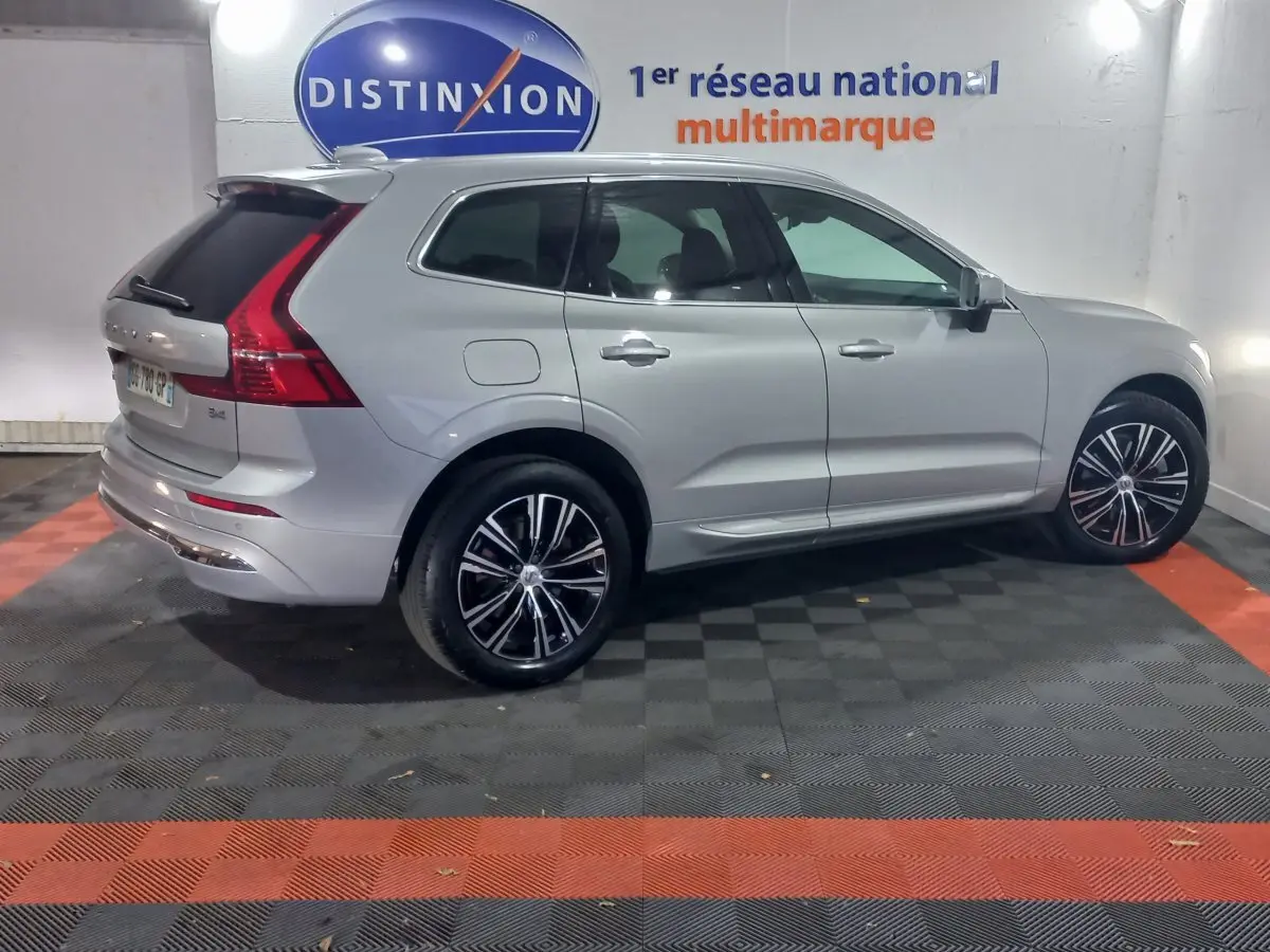 Vue côté gauche d'un Volvo XC60 gris clair B4 197 Geartronic 8 Inscription avec jantes noires et chrome en intérieur fermé.