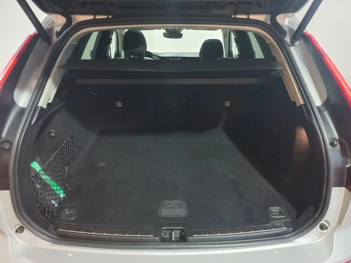 Coffre ouvert vu de l'arrière d'un Volvo XC60 gris clair, avec filet de sécurité et banquette arrière visible.