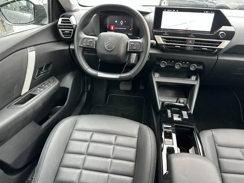 Intérieur de la Citroën C4 X 2025 vu de face, montrant le tableau de bord numérique et la console centrale noire brillante.