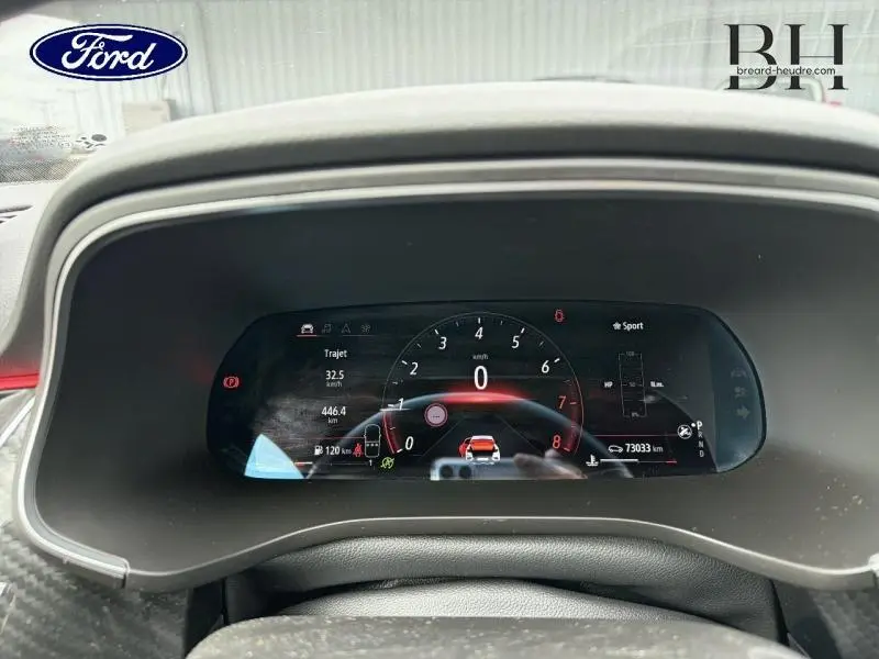 Tableau de bord numérique de Renault Arkana gris métallisé, affichage vitesse et mode Sport en vue frontale rapprochée.