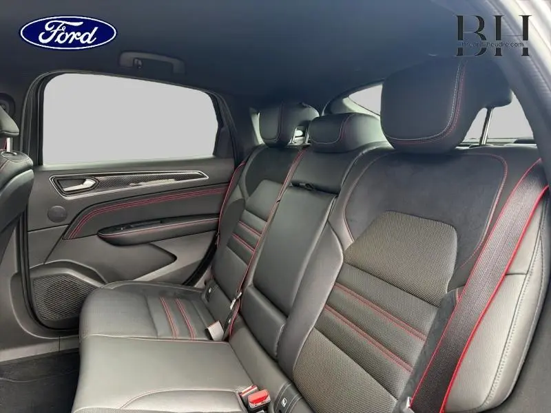 Vue intérieure arrière droite du Renault Arkana 2023 gris métallisé, sièges cuir noir avec surpiqûres rouges.