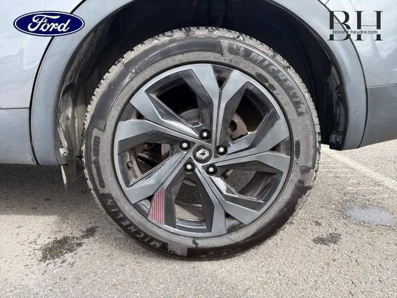 Gros plan sur la roue avant droite gris métallisé d'un Renault Arkana 2023 avec jante alu noire et logo Renault central.