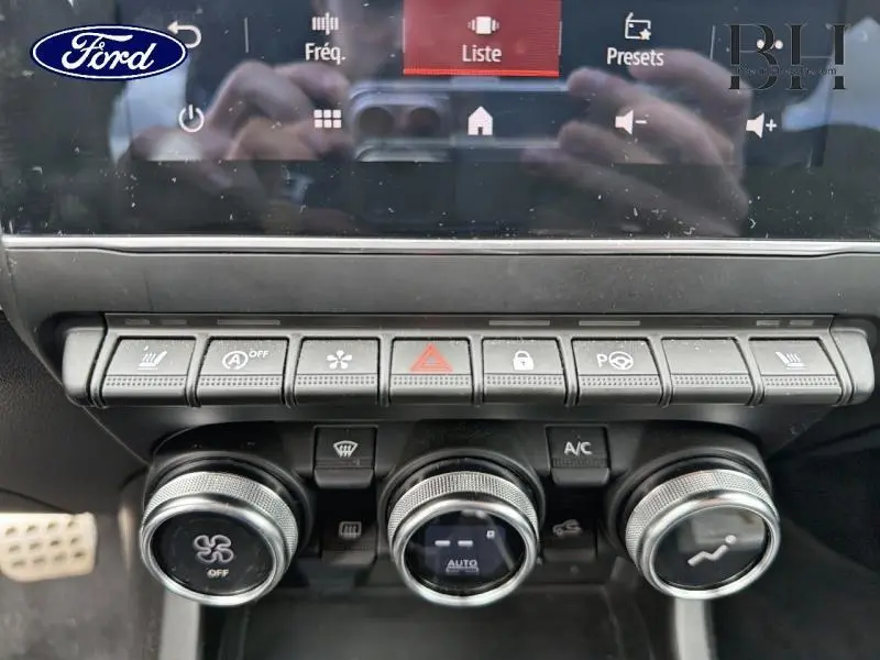 Tableau de bord avec commandes climatisation et boutons multifonctions d'une Renault Arkana gris métallisé vue de face.