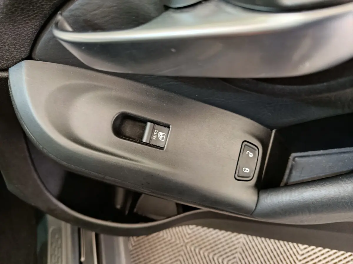 Gros plan sur la commande de lève-vitre et verrouillage de porte côté conducteur d'une FIAT 500X blanche.
