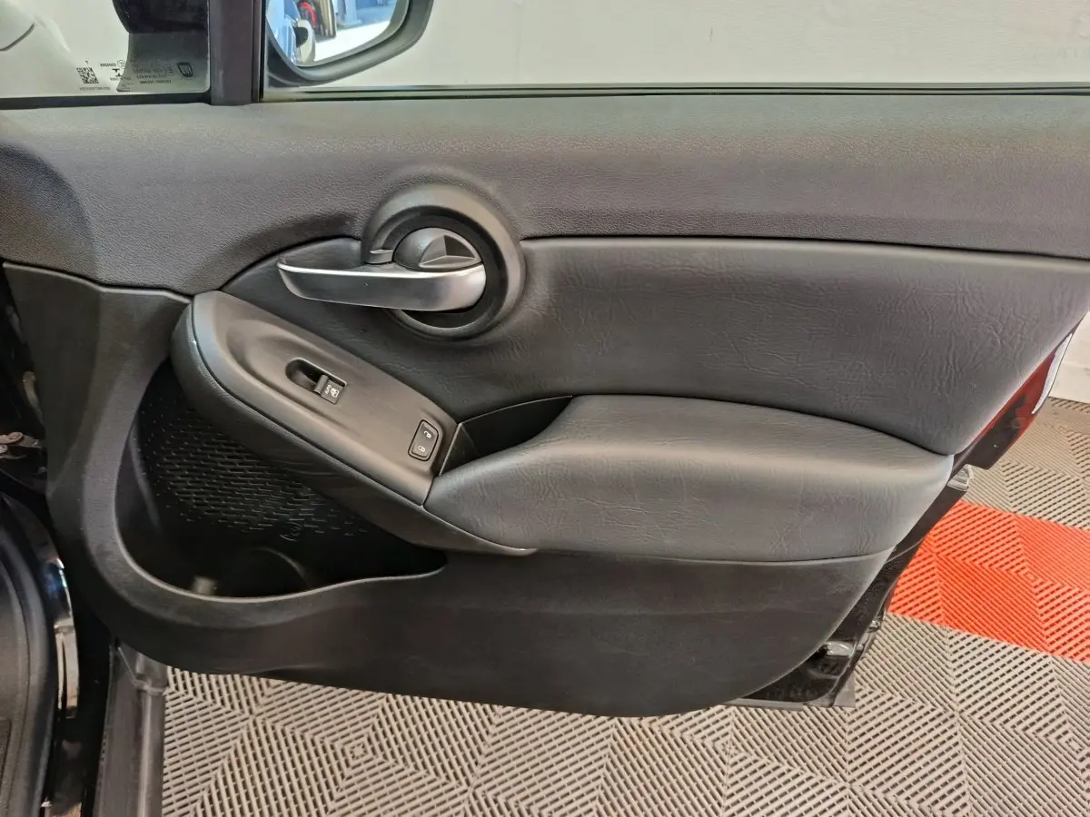 Gros plan sur la porte intérieure côté conducteur noire de la FIAT 500X avec poignée argentée et commandes électriques.