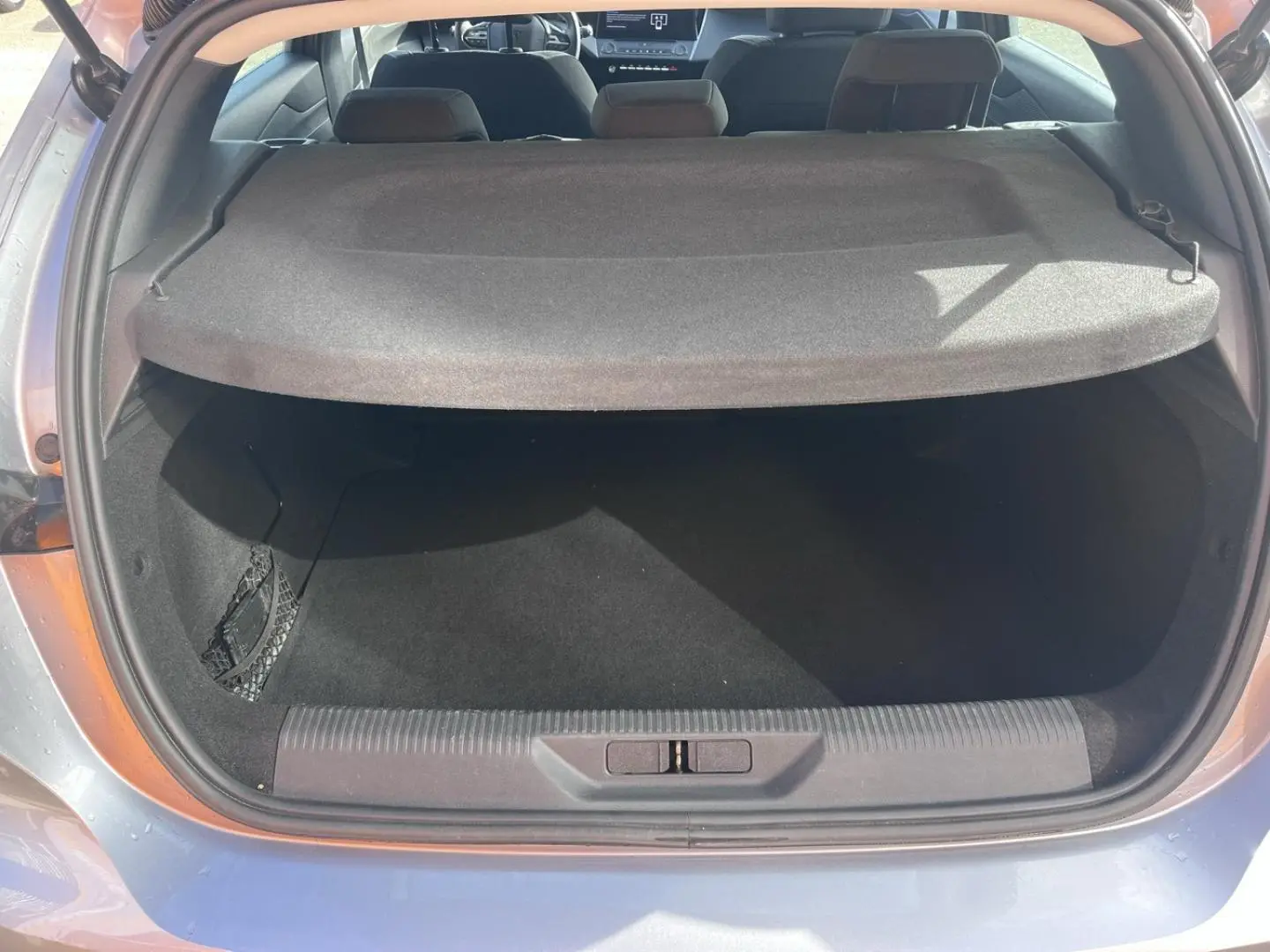 Coffre ouvert vu de l'arrière d'une Peugeot 308 gris Artense avec cache-bagages et banquette arrière visible.