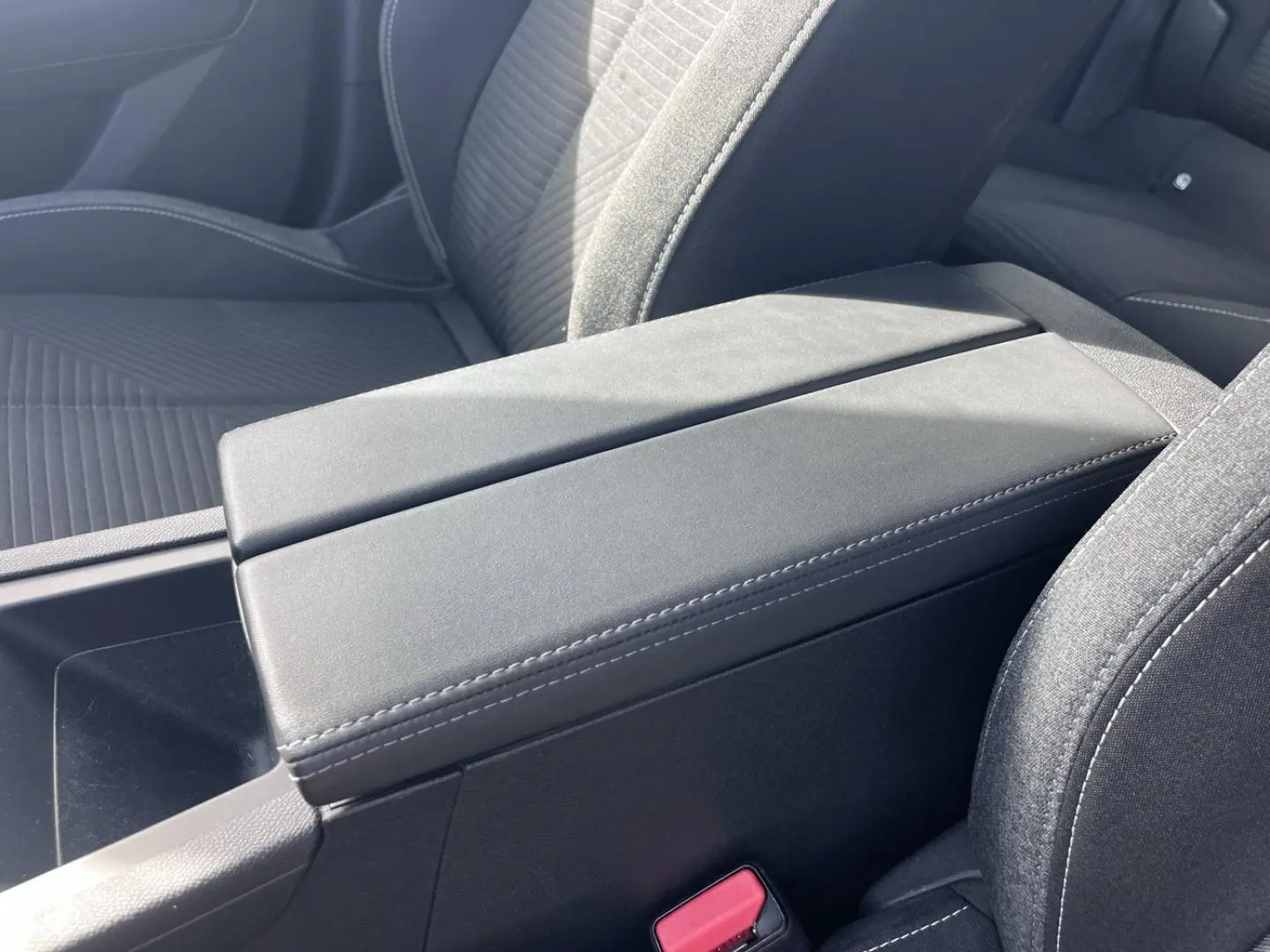 Accoudoir central avant gris avec rangement, sièges tissu noir à surpiqûres blanches dans Peugeot 308 2024.