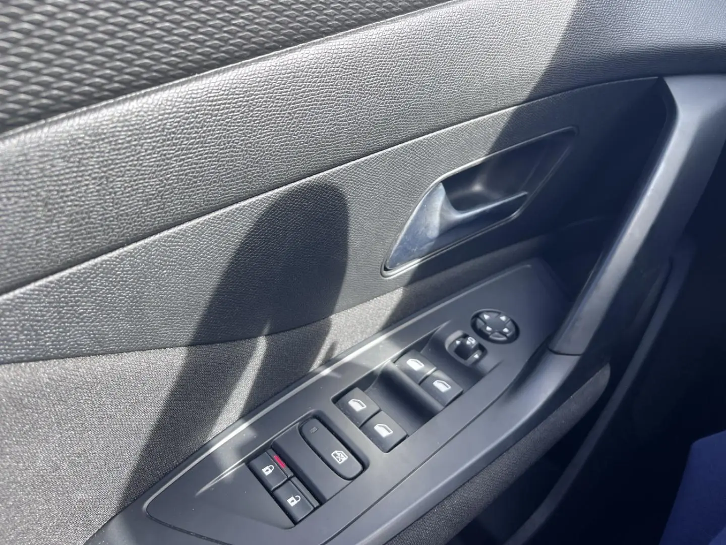 Vue rapprochée de la porte côté conducteur de la Peugeot 308 2024, avec commandes électriques et poignée noire.