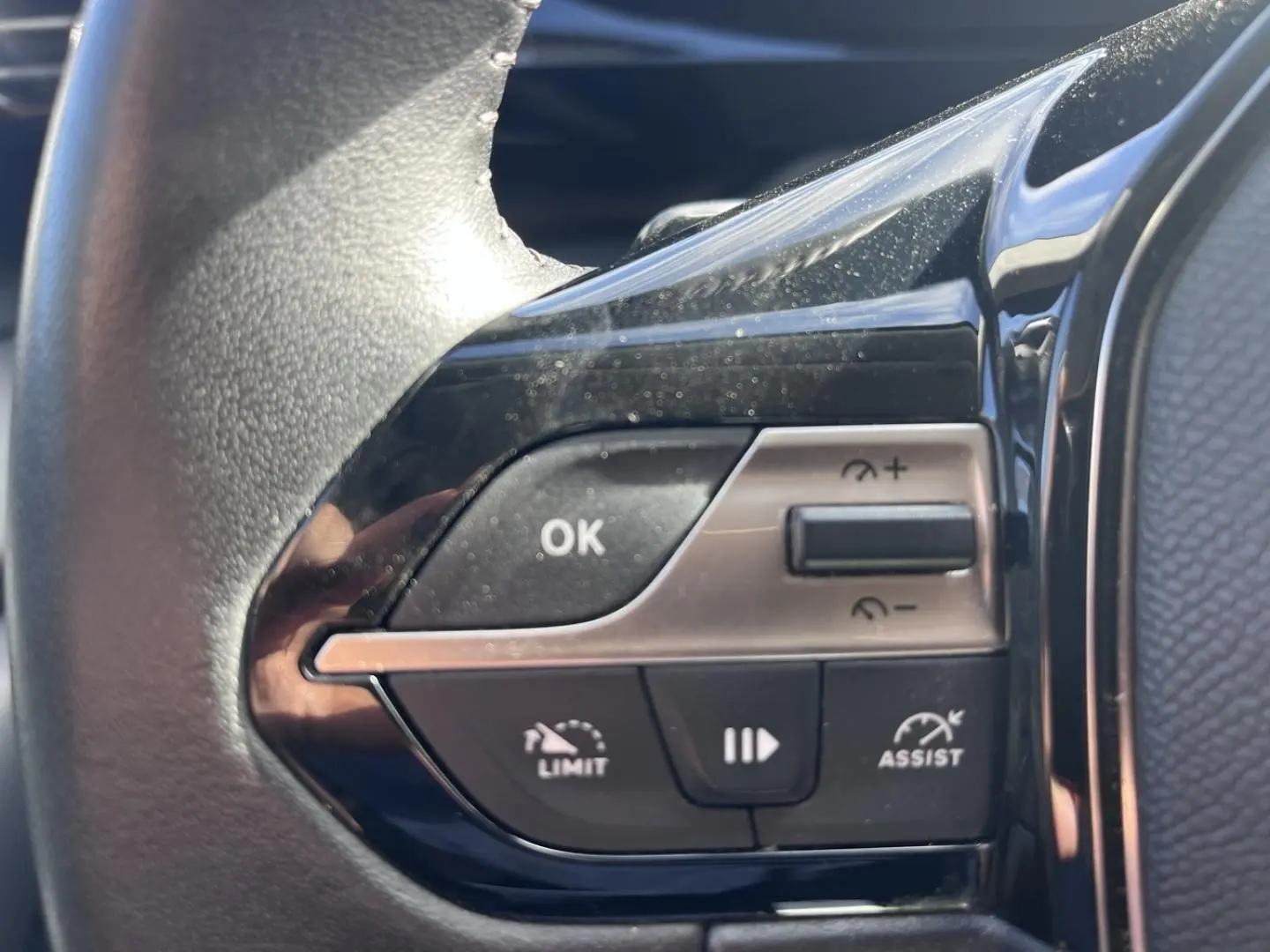 Gros plan sur les commandes du volant multifonction côté gauche d’une Peugeot 308 gris Artense 2024.