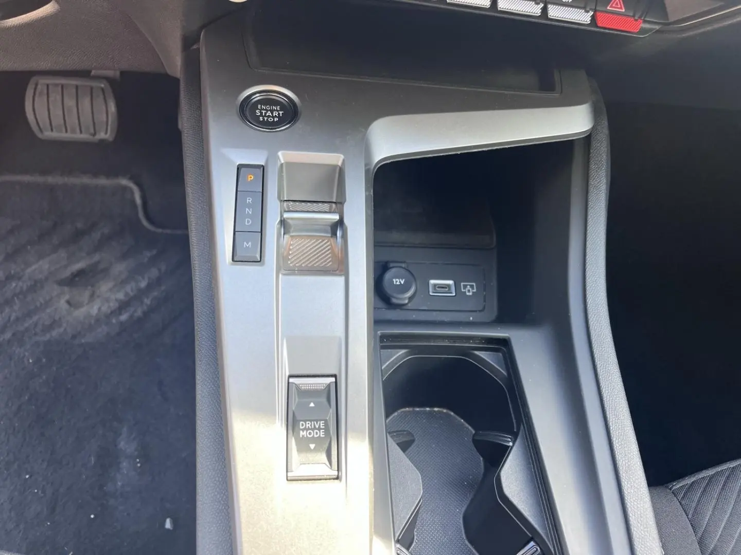 Vue rapprochée de la console centrale grise de la Peugeot 308 2024 avec sélecteur de boîte auto et prise 12V visible.