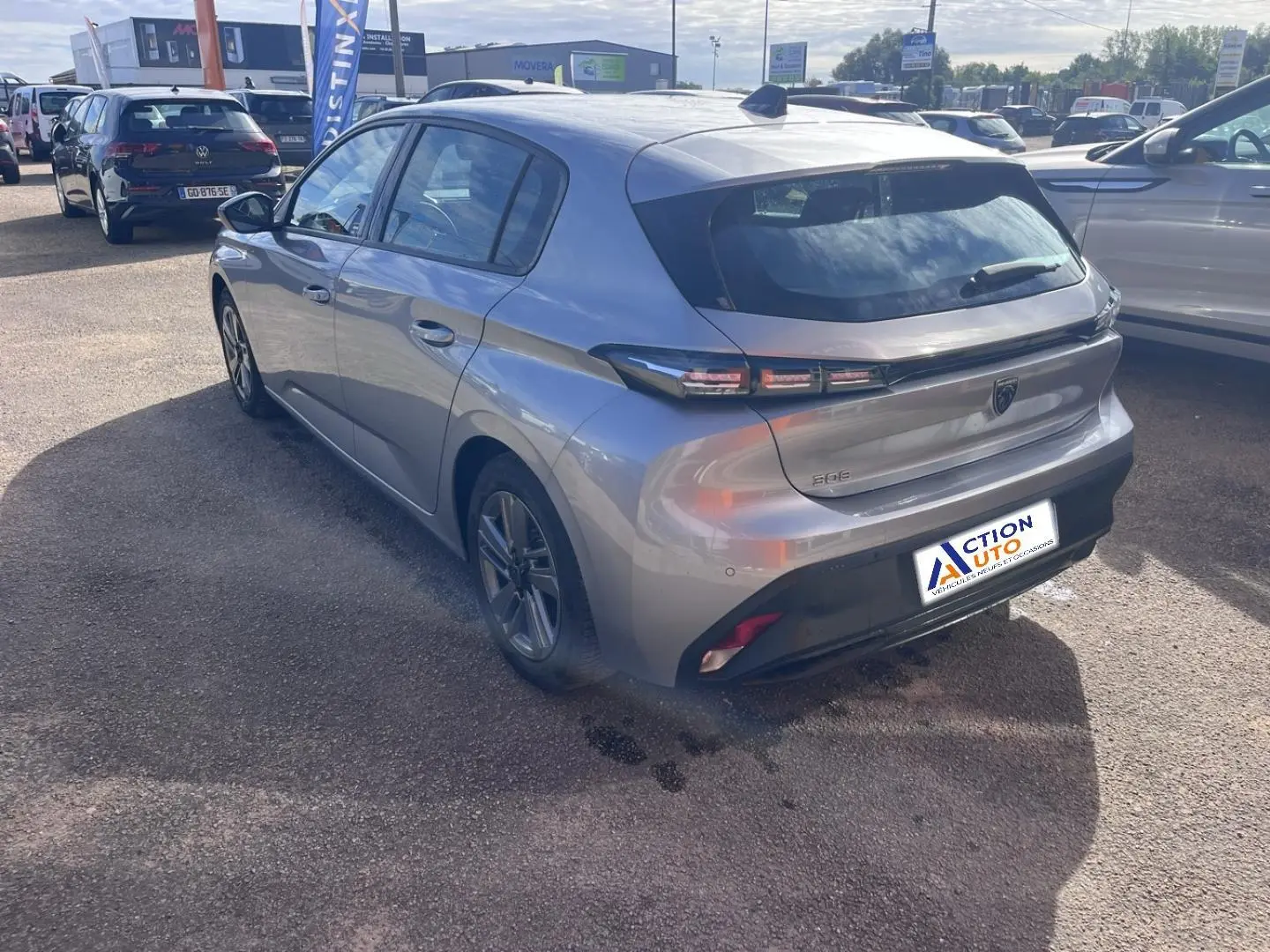 Peugeot 308 gris Artense vue 3/4 arrière droit, feux arrière LED et jantes alu visibles sur parking extérieur.