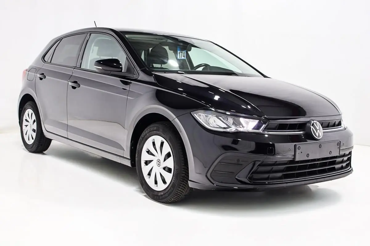 Volkswagen Polo noire vue en 3/4 avant droit, avec jantes blanches et calandre épurée sur fond blanc.