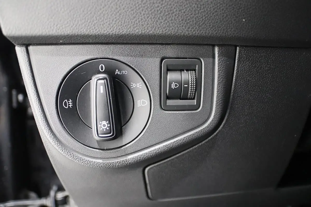 Gros plan sur le bouton de commande des phares et réglage d'intensité dans un Volkswagen Polo noir 2022.