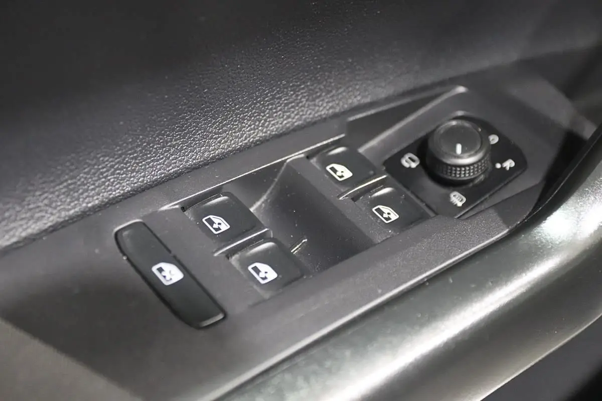 Gros plan sur les commandes électriques des vitres et rétroviseurs côté conducteur d'une Volkswagen Polo noire 2022.