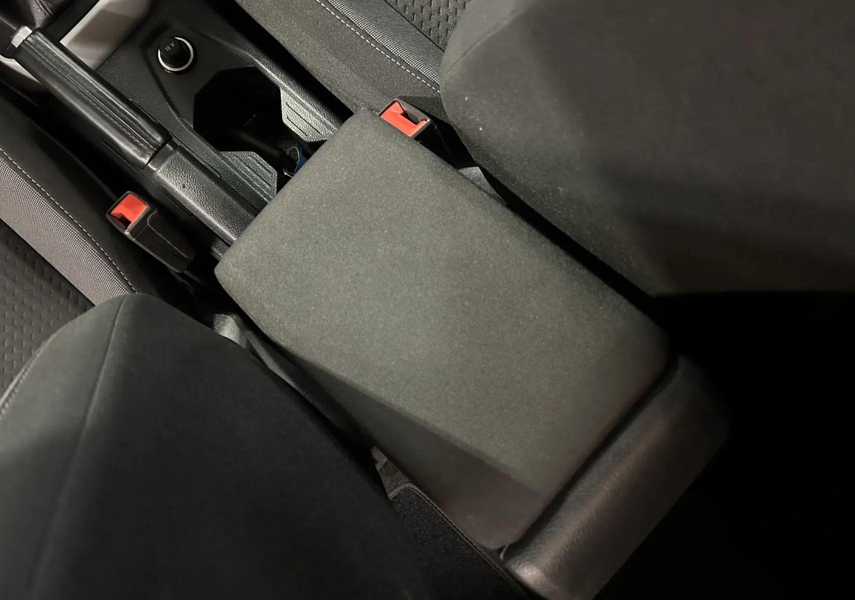 Vue rapprochée de l'accoudoir central et des sièges en tissu noir de la Volkswagen Polo 2022.