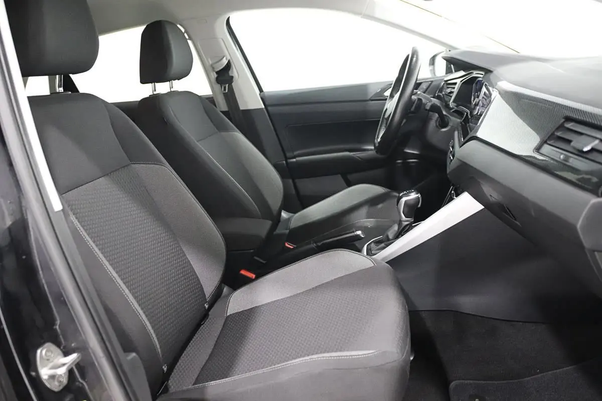 Vue intérieure côté conducteur de la Volkswagen Polo noire 2022 avec sièges tissu et tableau de bord moderne.