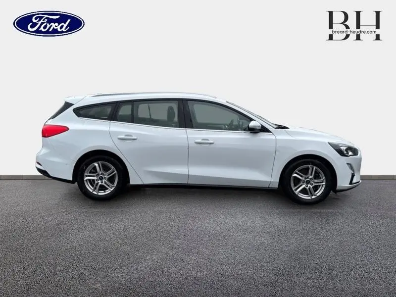 Profil droit d'une Ford Focus SW 2020 blanc glacier avec jantes alu et barres de toit visibles.