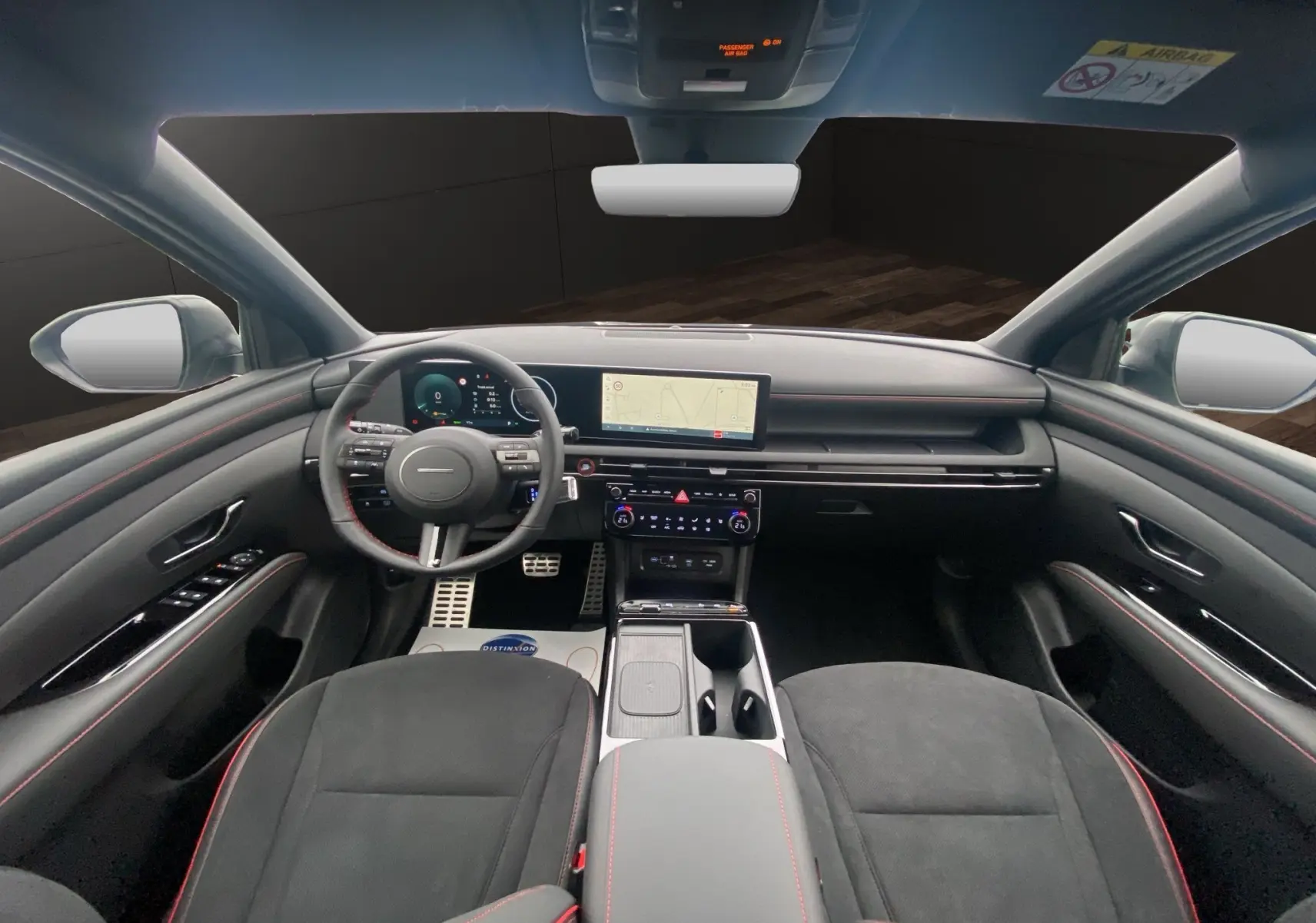 Vue intérieure avant du Hyundai Tucson 2026 avec tableau de bord noir, volant cuir multifonction et écran GPS central.