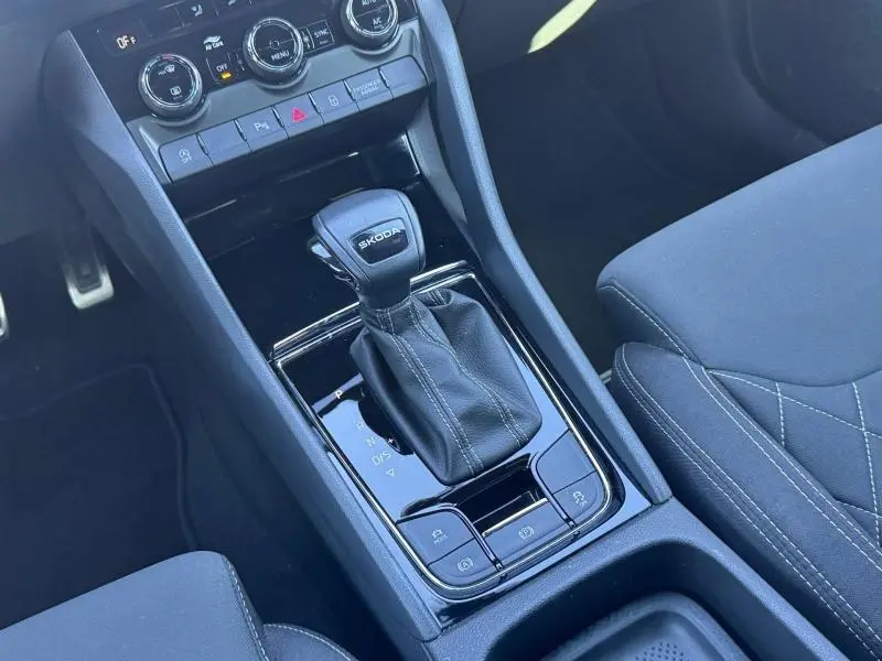 Vue rapprochée de la console centrale noire avec levier de vitesses automatique SKODA et sièges tissu noir du Karoq 2025.