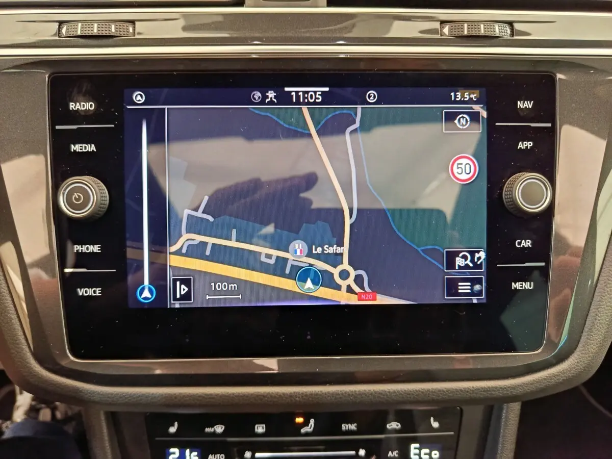 Écran tactile central du Volkswagen Tiguan 2023 affichant la navigation, entouré de commandes noires brillantes.