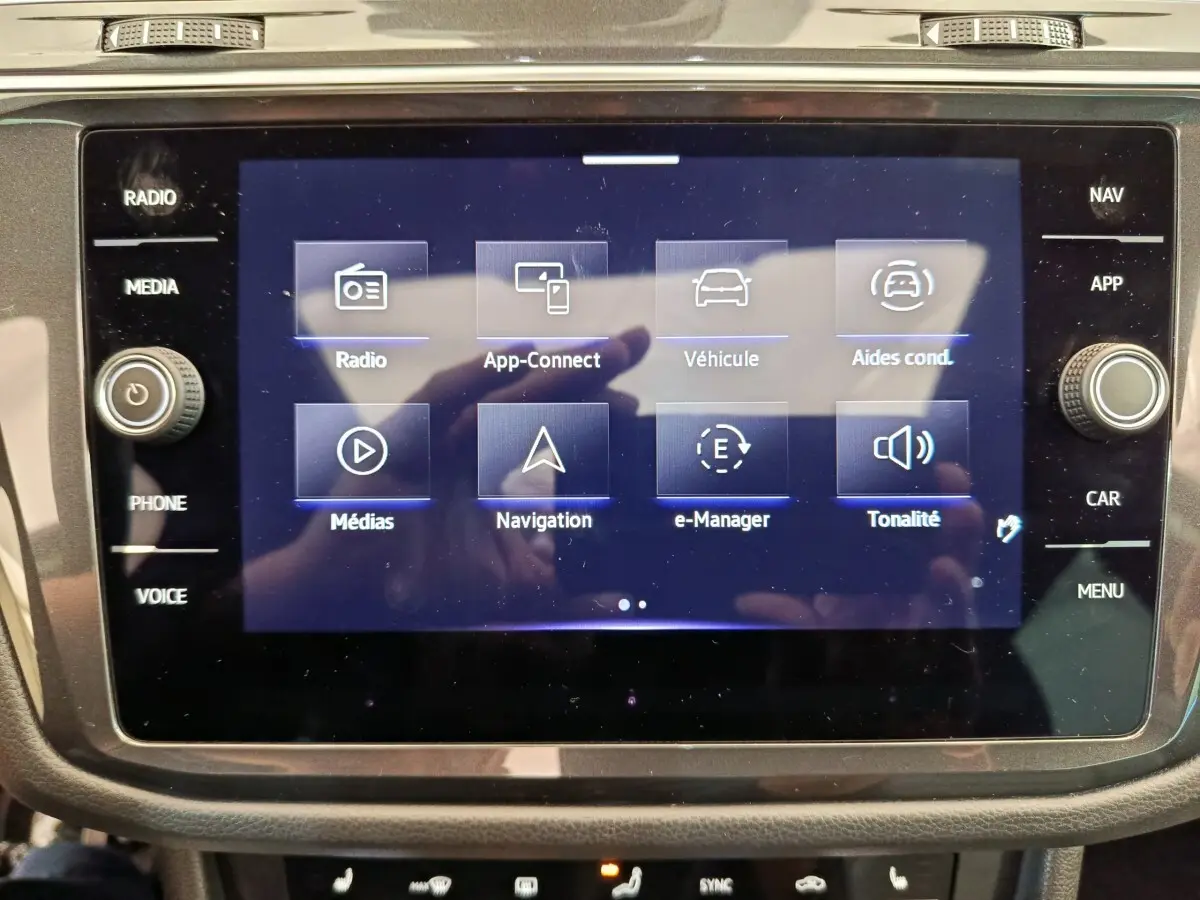 Écran tactile central du Volkswagen Tiguan 2023 affichant les options radio, navigation et aides à la conduite.