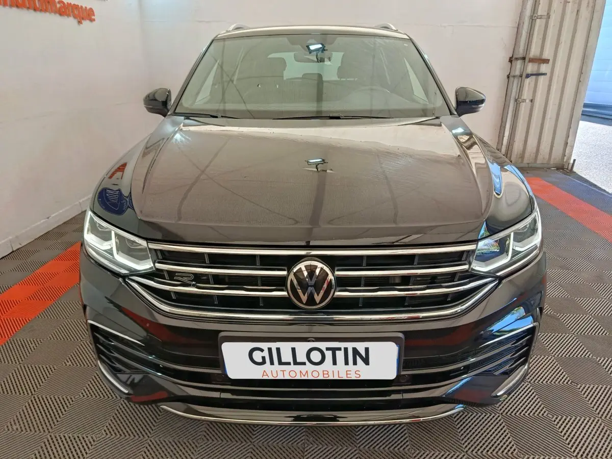 Vue avant du Volkswagen Tiguan noir 1.4 eHybrid R-Line Exclusive avec calandre chromée et phares LED allumés.