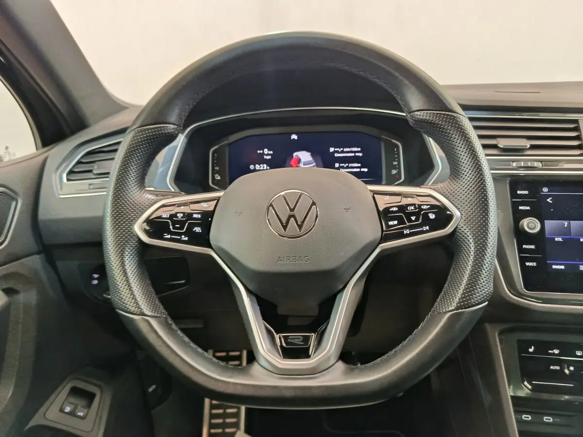 Vue intérieure centrée sur le volant cuir multifonctions du Volkswagen Tiguan noir avec tableau de bord digital.
