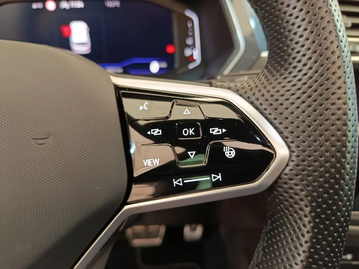 Gros plan sur les commandes à droite du volant cuir perforé du Volkswagen Tiguan noir, affichage numérique en arrière-plan.