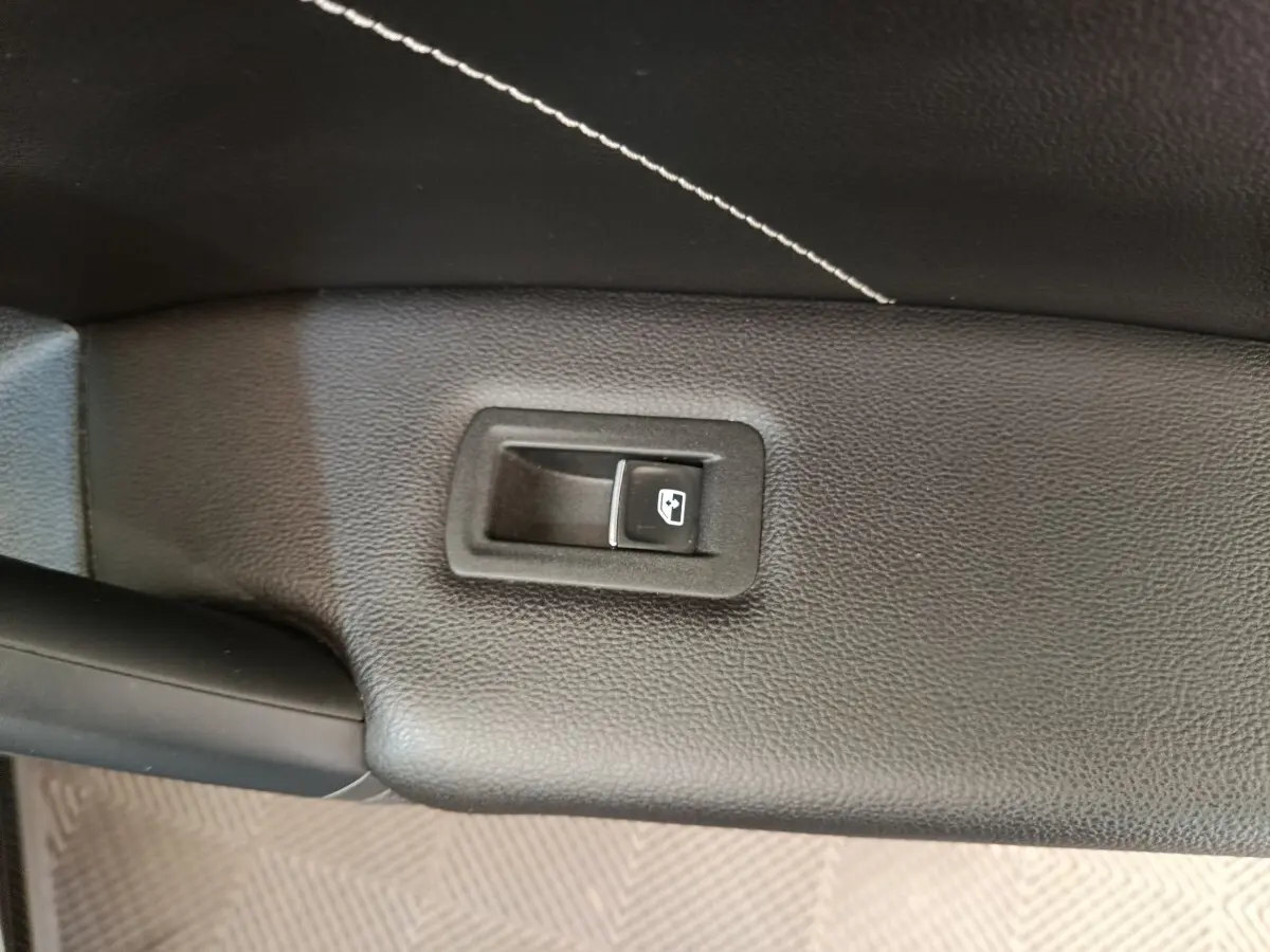 Bouton de commande de vitre électrique sur la porte intérieure en cuir noir du Volkswagen Tiguan 2023 hybride.