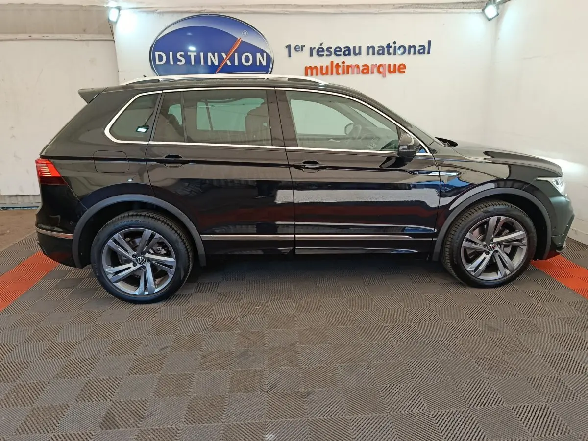 Vue latérale droite d'un Volkswagen Tiguan noir 1.4 eHybrid 2023 avec jantes alliage et toit ouvrant électrique.