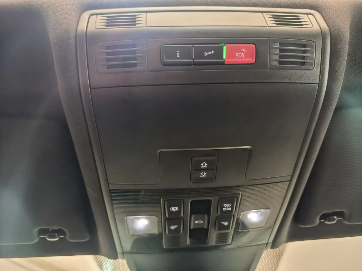 Vue du plafond intérieur du Volkswagen Tiguan 2023 noir, avec commandes d'éclairage et bouton SOS rouge allumé.