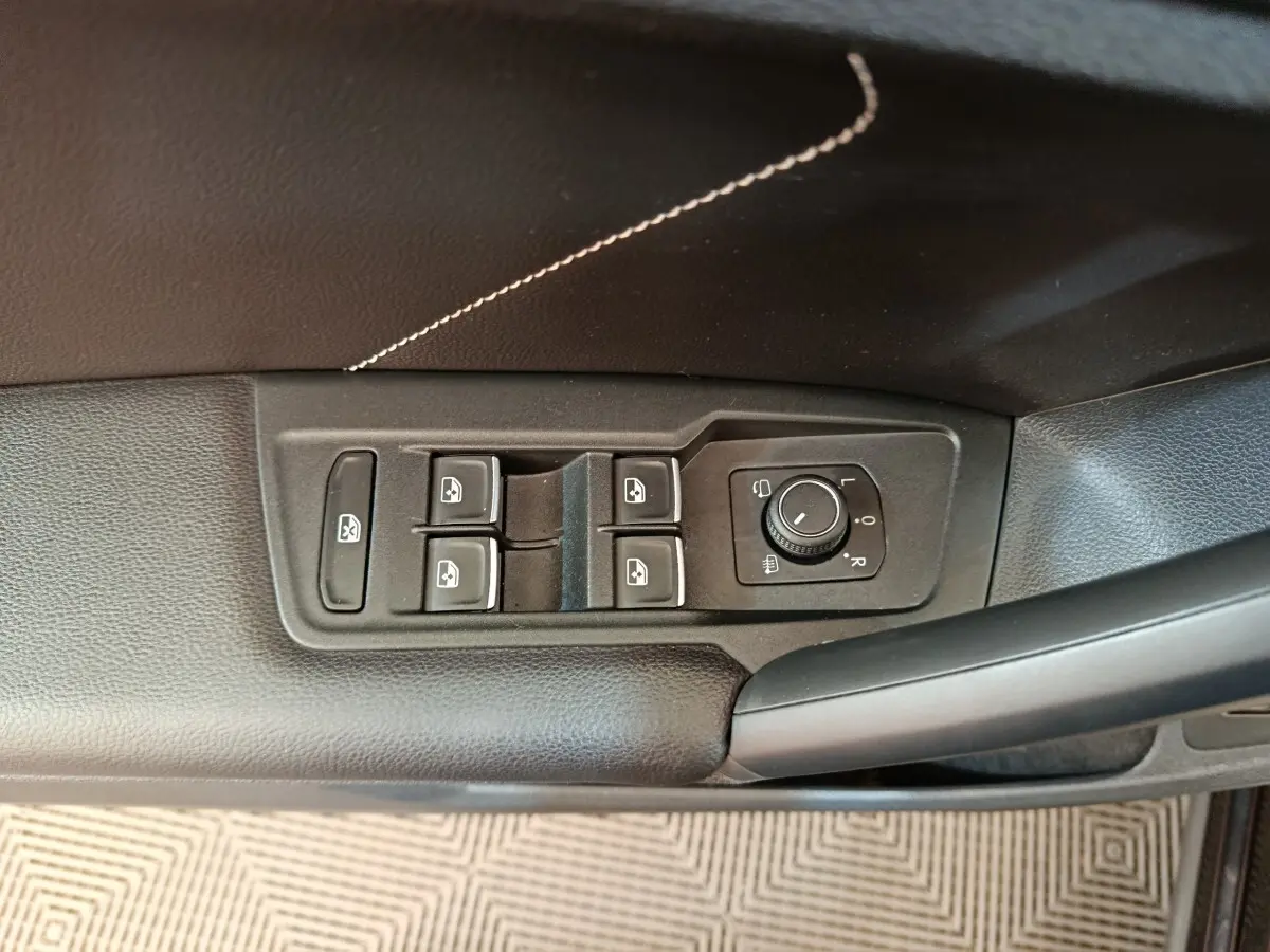 Vue rapprochée des commandes de lève-vitres et réglage des rétroviseurs côté conducteur du Volkswagen Tiguan noir 2023.