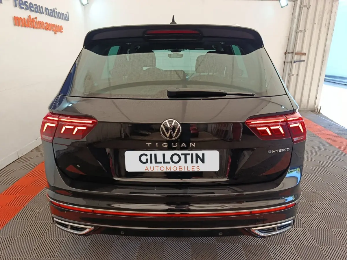 Vue arrière d'un Volkswagen Tiguan noir hybride rechargeable avec feux LED et double sortie d'échappement chromée.